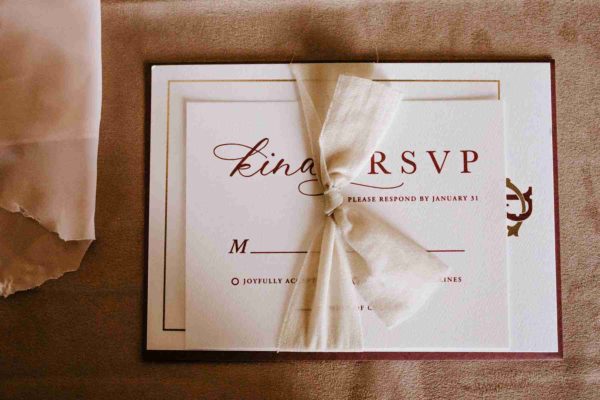 A beautifully designed wedding RSVP card tied with a ribbon. The card features a simple yet elegant design.