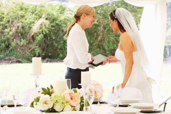 A lesbian wedding ceremony with a bride and her officiant. The bride is wearing a white wedding dress and veil.