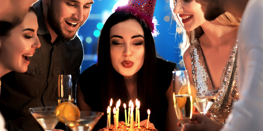 woman blowing out birthday candles with friends