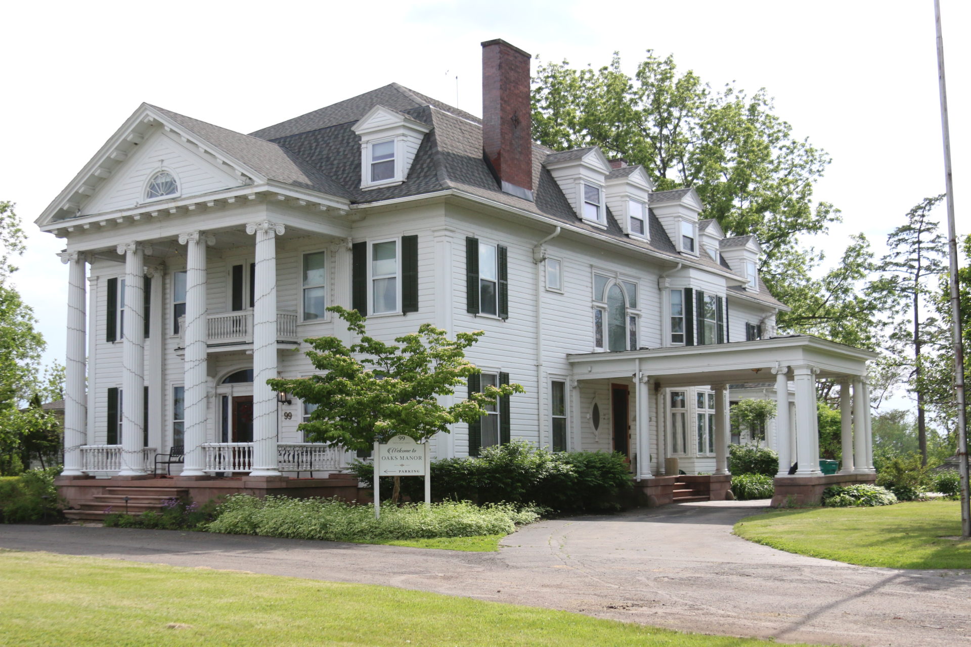 A large white house with columns and a porch. The house has a gray roof.