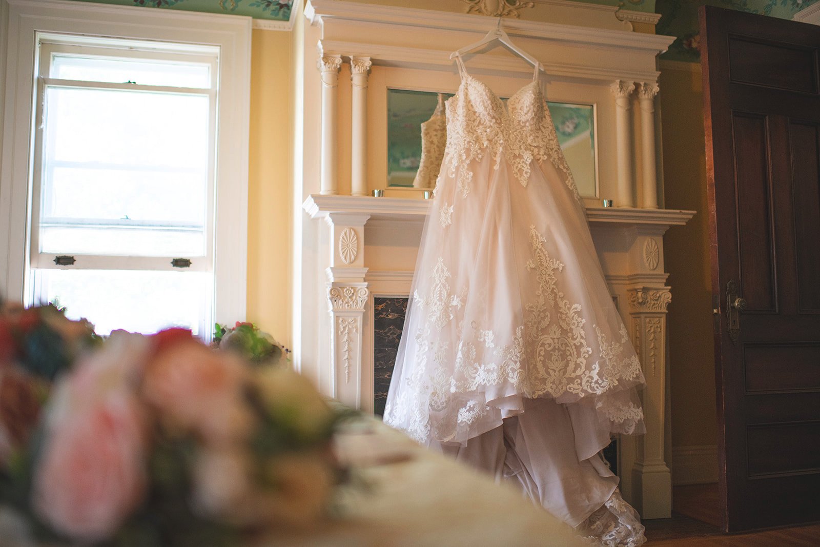 A beautiful wedding dress hanging on a white hanger. The dress is made of lace and has a sweetheart neckline.
