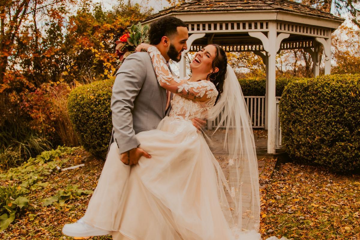 Happy newlywed couple embracing outdoors. Beautiful bride and groom smiling.