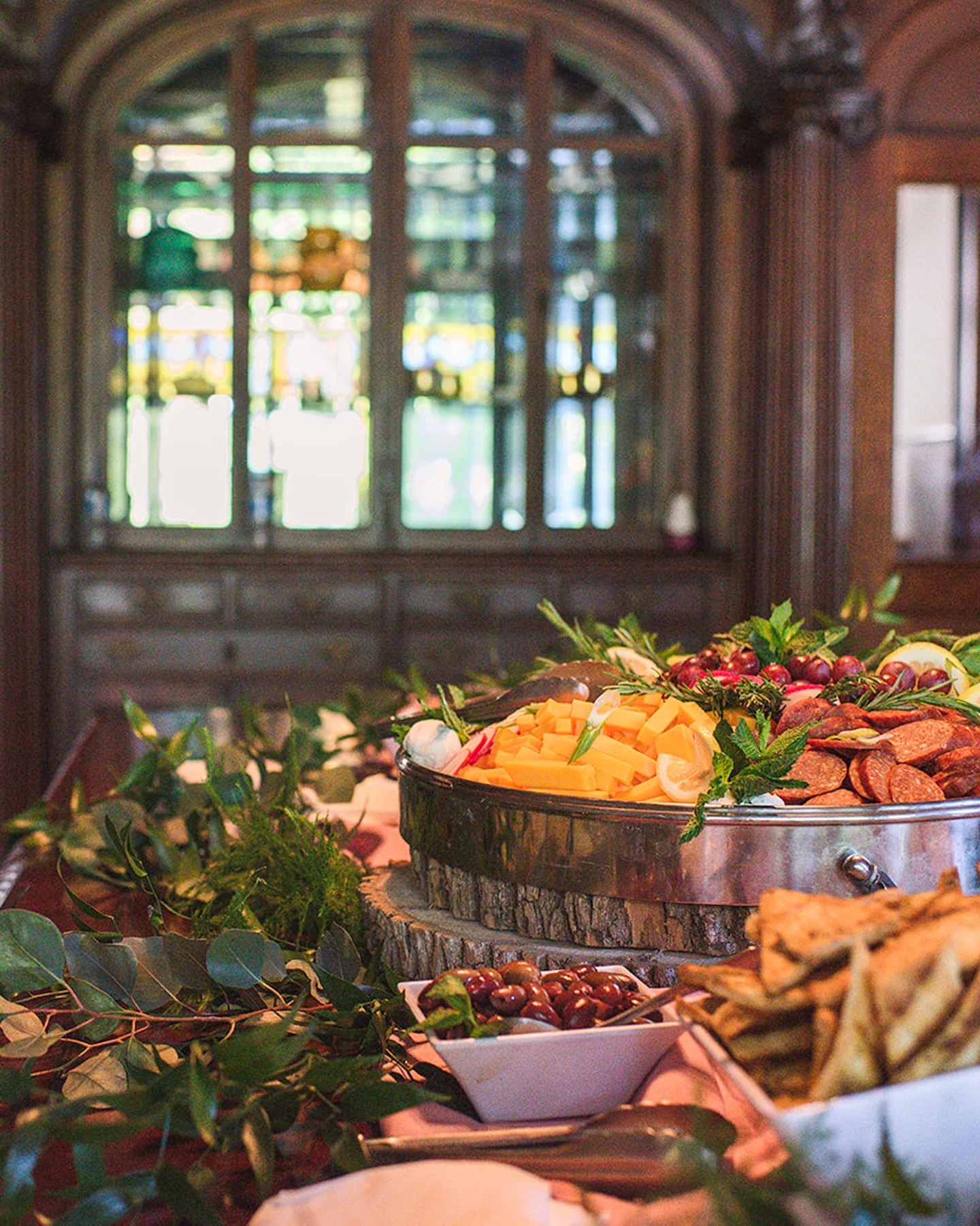 Catering spread with food and garnishes A table with various foods and green leaves. A large bowl of food in the center.