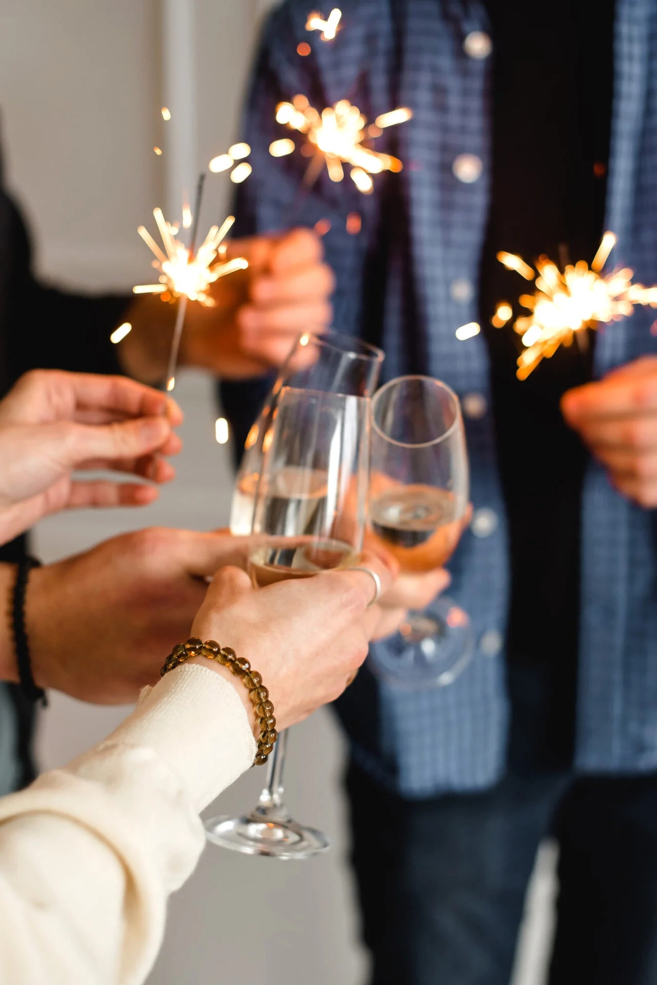 Hands holding sparklers and wine glasses Celebration with sparklers and champagne