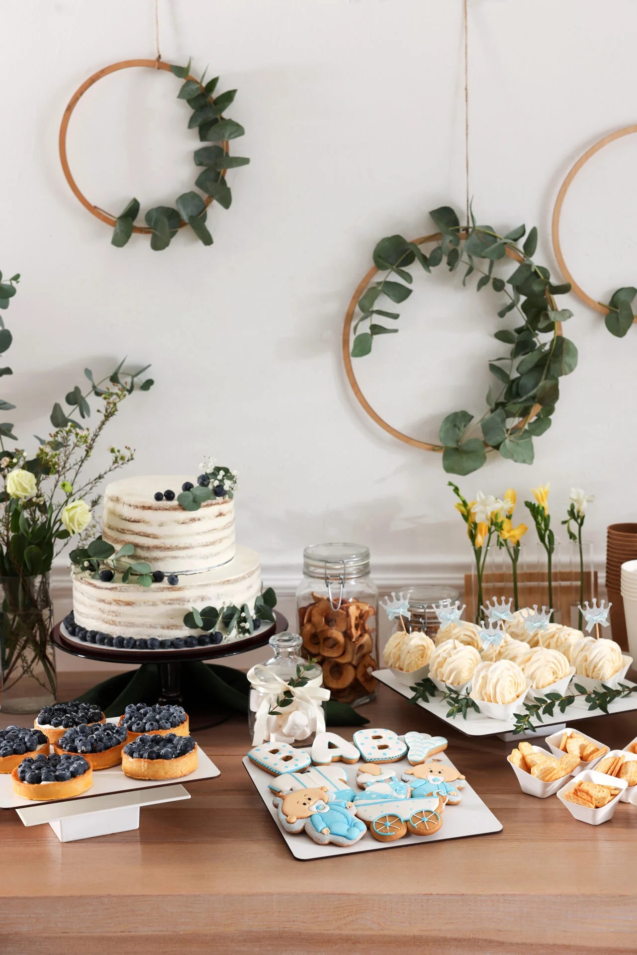 Delicious desserts on a wooden table A variety of sweet treats on a table. A cake and cupcakes with white frosting.