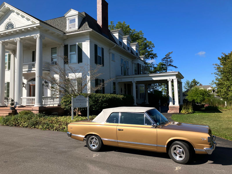 A gold vintage car parked on a street. The car has a white roof.