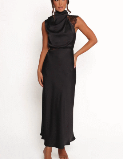 A woman wearing a long dress. She is posing with one hand on her hip.