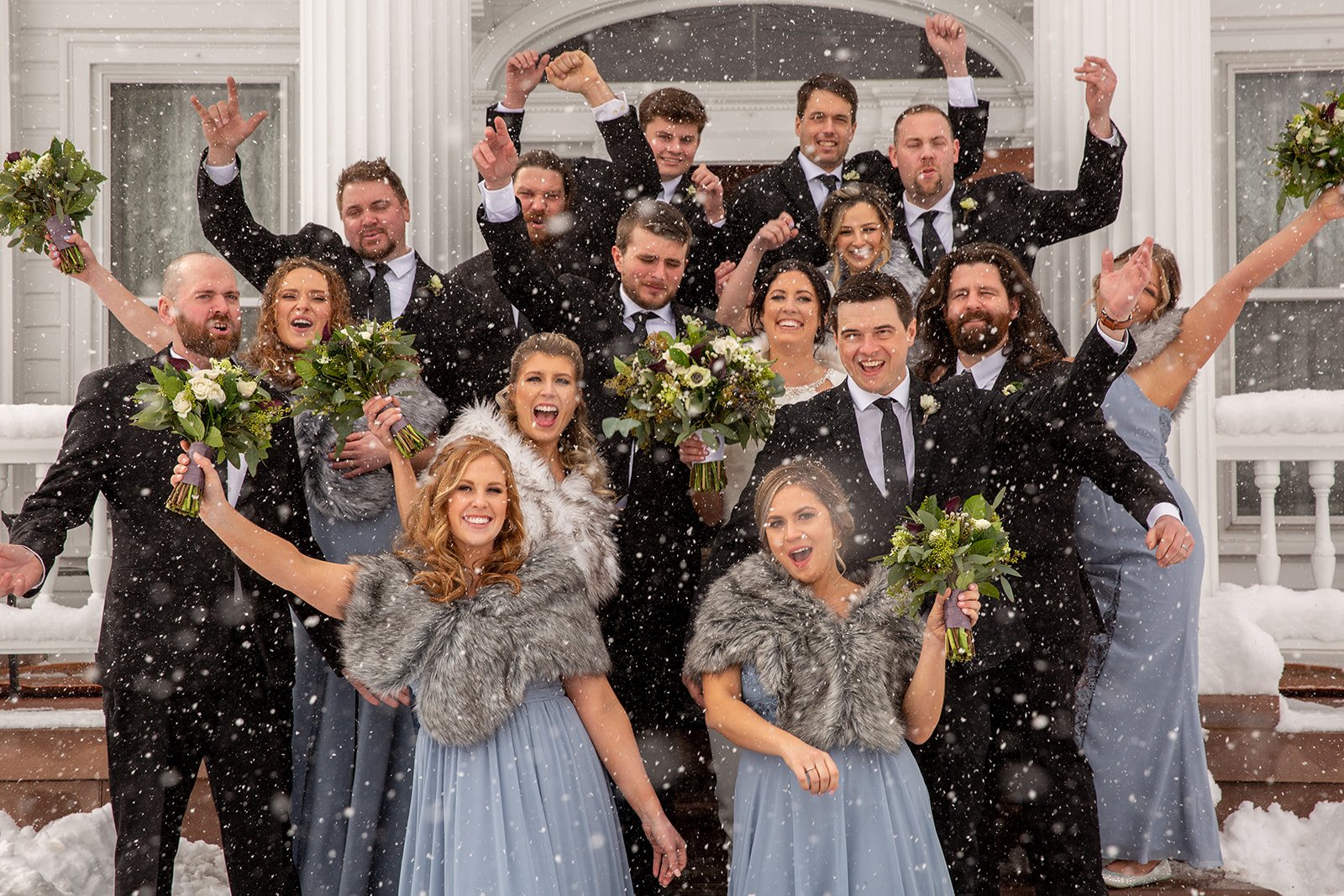 Wedding party in formal attire throwing bouquets. Snow falling.
