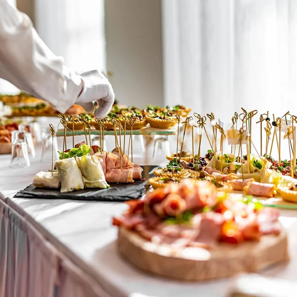 Catering staff preparing food at a buffet Catering staff member preparing dishes at a buffet table. Variety of food
